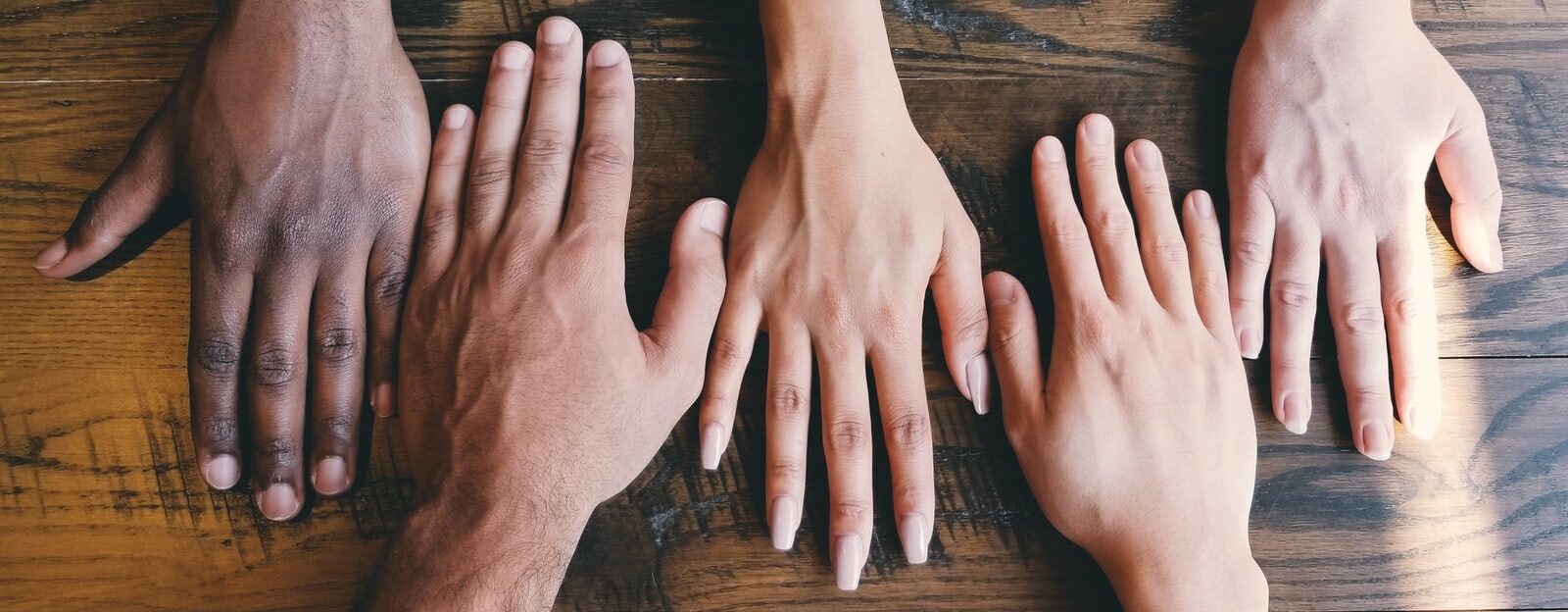 five human hands on brown surface